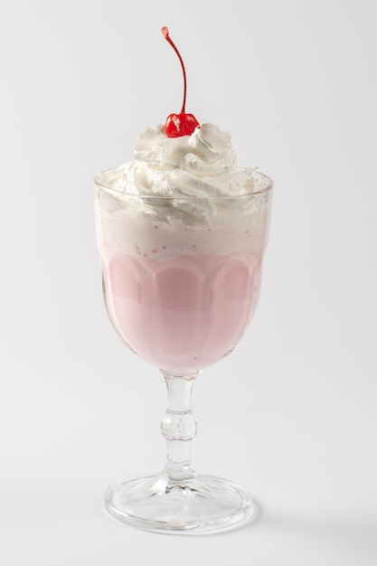 Cherry milk protein shake, with whipped cream and cherry syrup on a white plate.