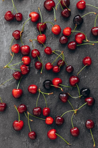 Cherry pattern Flat lay of cherries and leaves on a dark backgroundTop view