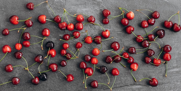 Cherry pattern Flat lay of cherries and leaves on a dark backgroundTop view