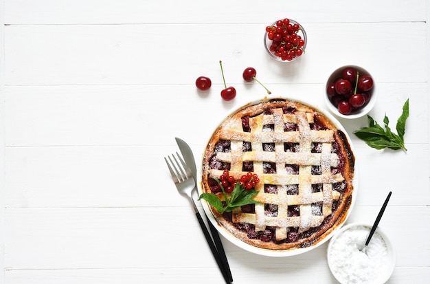 Cherry pie on a white wooden background with place for text. Tart with a cherry. View from above. Layout