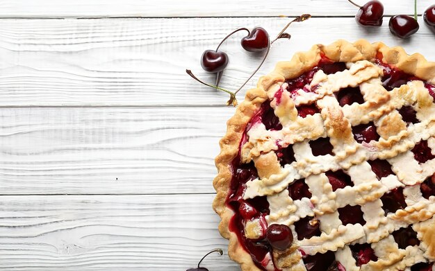 Cherry pie on a white wooden background with place for text Tart with a cherry