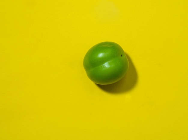 黄色の背景にチェリー プラム フルーツ健康的な緑の果物南部の果物を分離します