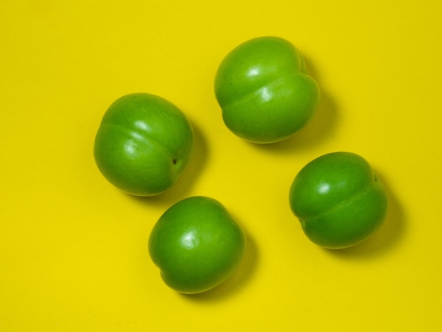 黄色の背景にチェリー プラム フルーツ健康的な緑の果物南部の果物を分離します