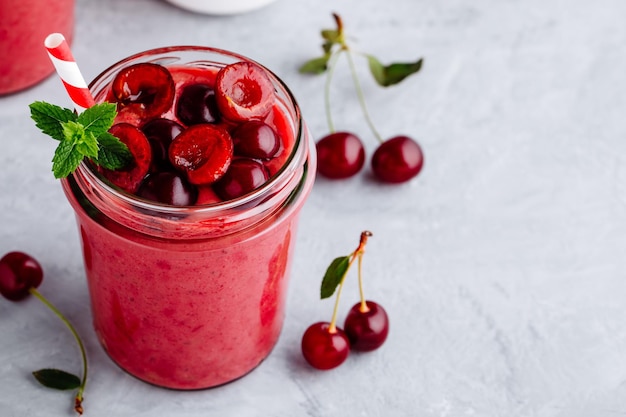 Cherry smoothie in glass jars with mint leaves and fresh berries