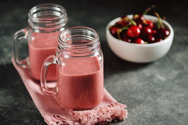 Cherry smoothie with milk in glass jars