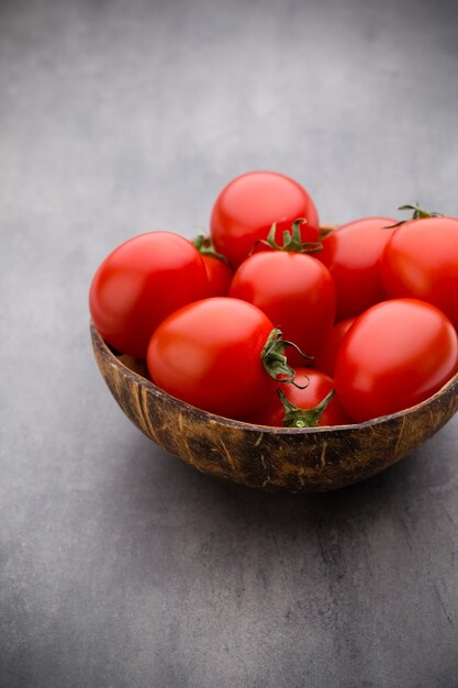 Cherry tomaten in een houten kom op een grijze achtergrond