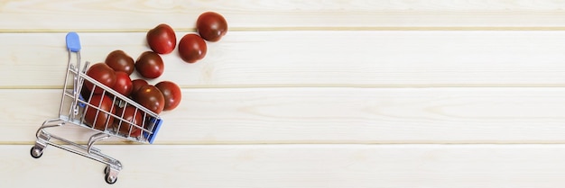 Cherry Tomaten in een metalen winkelwagentje op een achtergrond van lichte houten planken