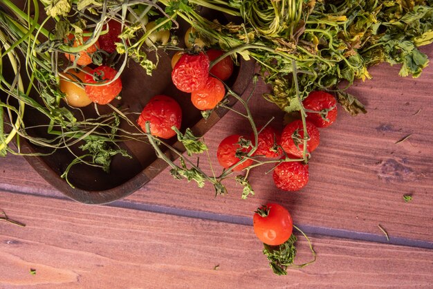 Cherry Tomaten, rottende kerstomaten en rottende groene geur op houten oppervlak op een tafel, donkere achtergrond, bovenaanzicht.