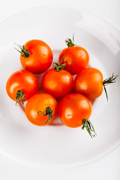 Photo cherry tomatoes for adding to pizza on a white plate