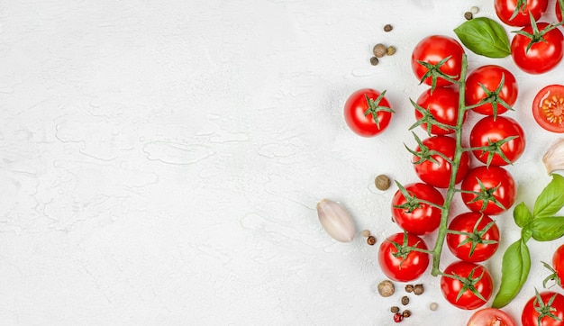 Cherry tomatoes, basil, garlic and peppercorns on a light concrete background