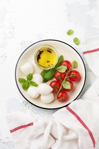 Cherry tomatoes, basil, mozzarella cheese and olive oil on white