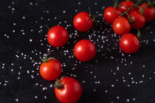 Cherry tomatoes on a branch on a dark background with sprinkled salt