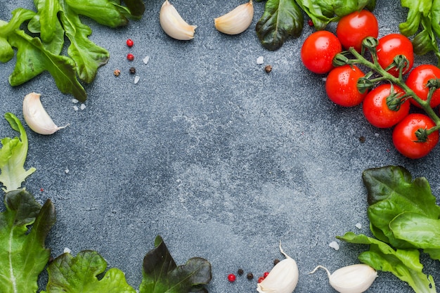 Cherry tomatoes on a branch Fresh herbs and garlic clove with spices on a dark stone table