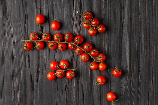 Cherry tomatoes on branches on a dark wooden background top view Fresh cherry tomatoes on a textured background Organic vegetables veganism