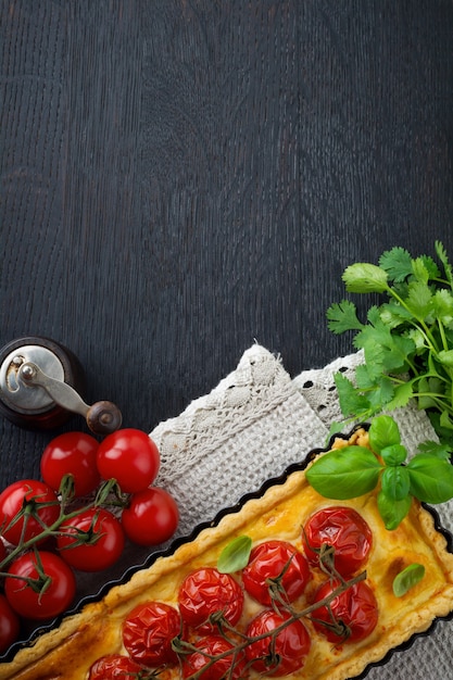 Cherry tomatoes and cheese tart on a dark background.