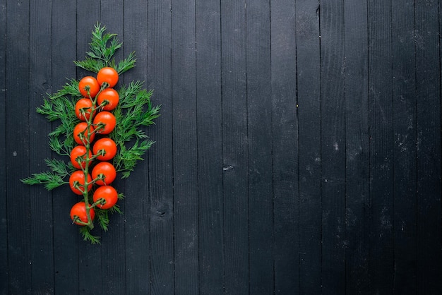 Cherry tomatoes and greenery On a wooden background Top view Free space for your text