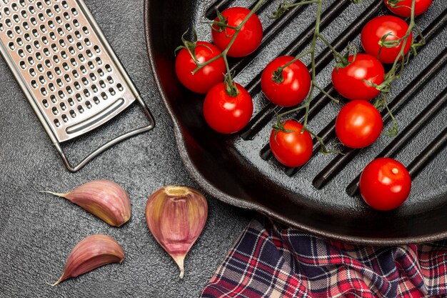 Cherry tomatoes in a pan Garlic cloves grater and napkin