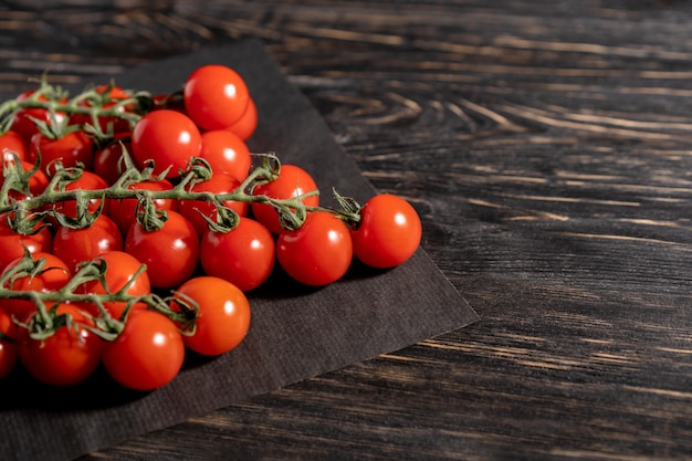 Cherry tomatoes in the paper packaging on the wooden table