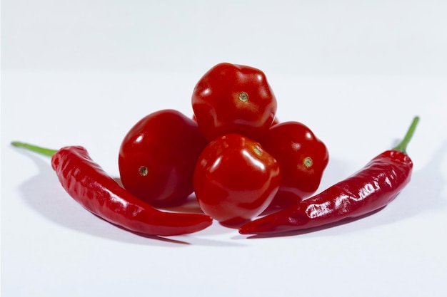 Cherry tomatoes and red chili peppers on a white background closeup