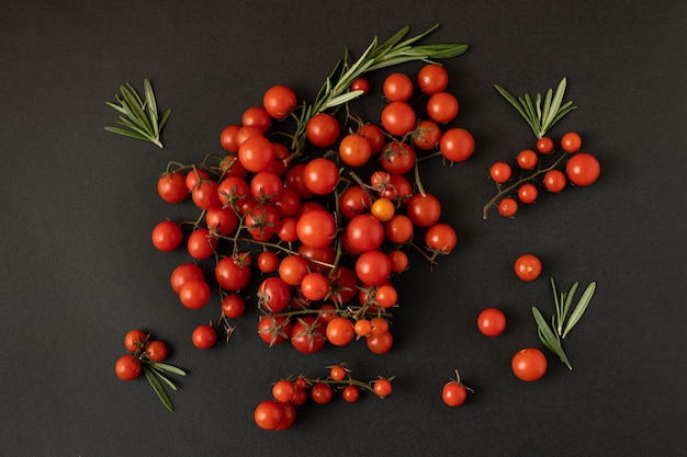 Cherry tomatoes and rosemary branches on a black background.