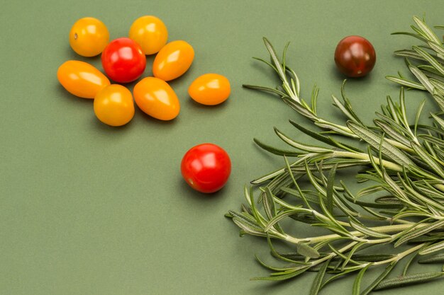Cherry tomatoes and rosemary on green surface