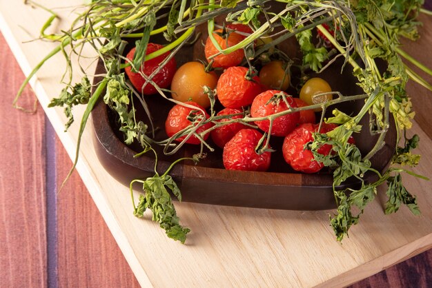 Cherry tomatoes, rotting cherry tomatoes and rotting green smell on wooden surface, dark background, selective focus.