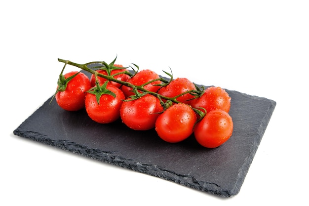 Cherry tomatoes on a slate cutting board isolate on a white background