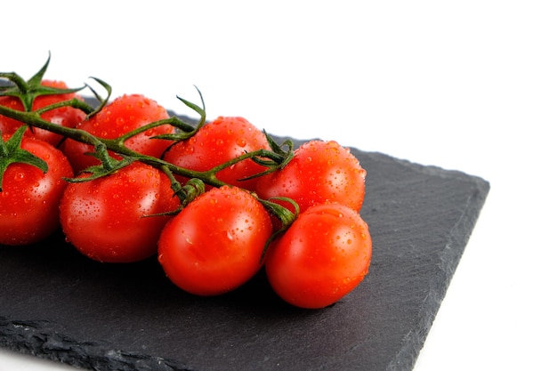 Cherry tomatoes on a slate cutting board isolate on a white background