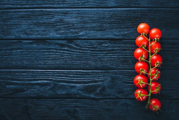 Cherry tomatoes on a twig on a wooden background. Top view.