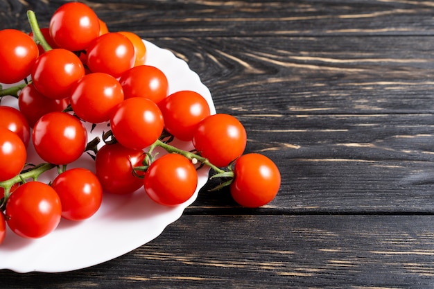 Cherry tomatoes in the white plate on the wooden table