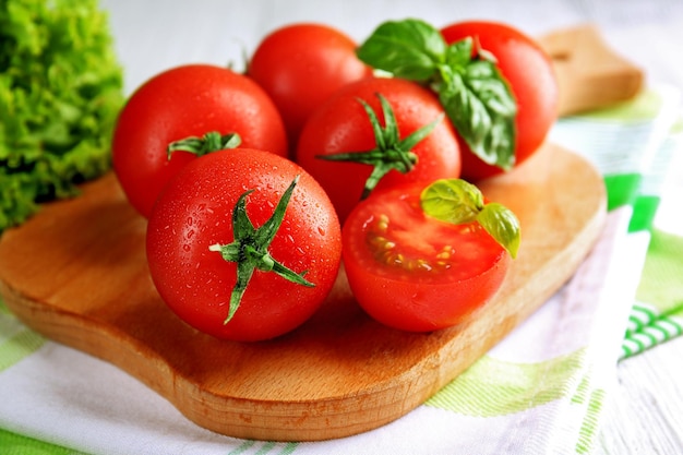 Cherry tomatoes with basil on wooden table close up