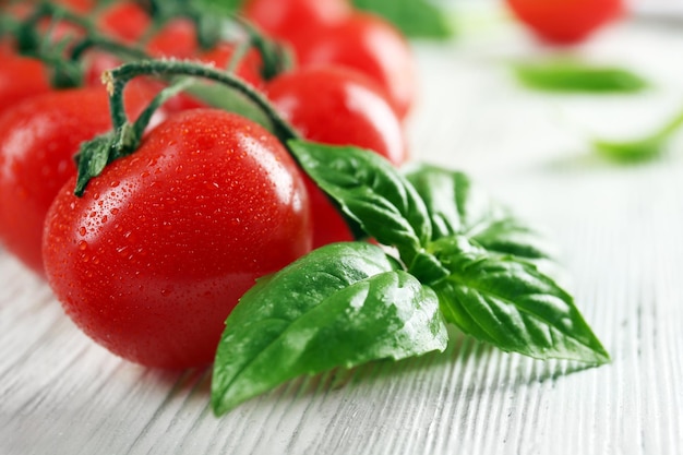 Foto pomodori di ciliegio con basilico su tavolo di legno da vicino