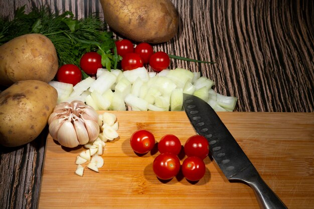 ナイフの横にある木の板にチェリートマトと野菜の菜食主義が健康的な食品を調理する