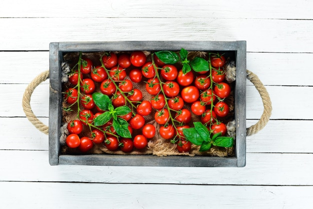 Photo cherry tomatoes in a wooden box top view free space for your text