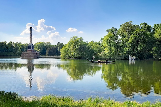 Chesme Column and gondola Catherine Park on lake under blue sky among greenery on sunny day