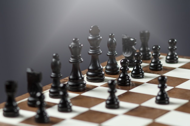 Chess board with black chess pieces on gray background