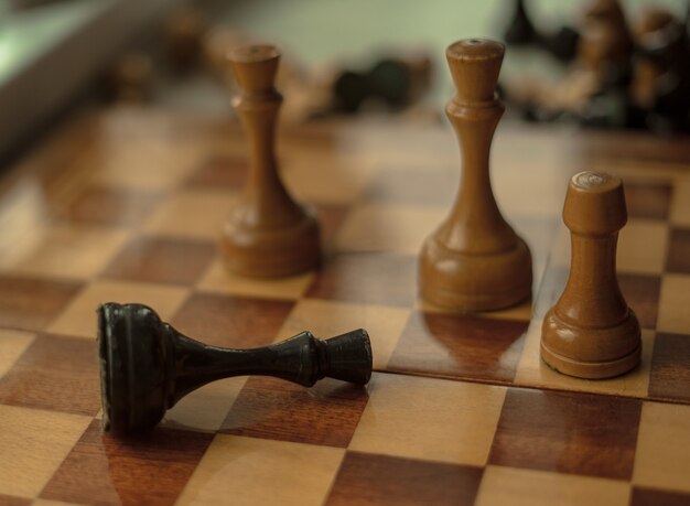 Chess game. Black king is checkmated and fallen on chessboard. game over. Old wooden chess