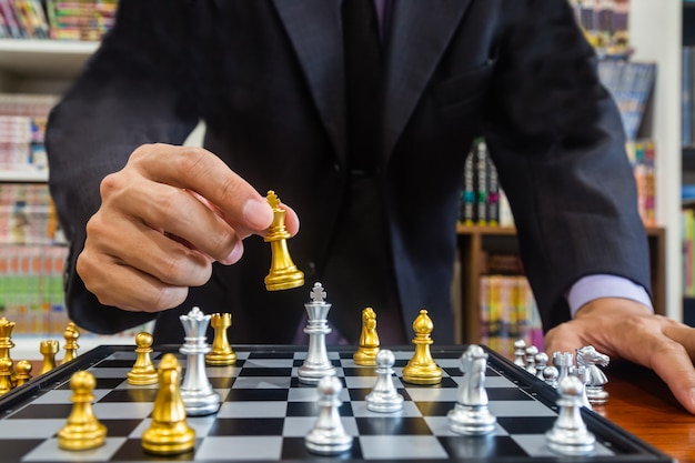 Chess game on chess board behind business man background. Business concept to present financial information and marketing strategy analysis.