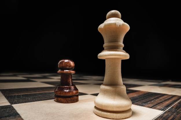 Chess game with chess pieces against black background close up