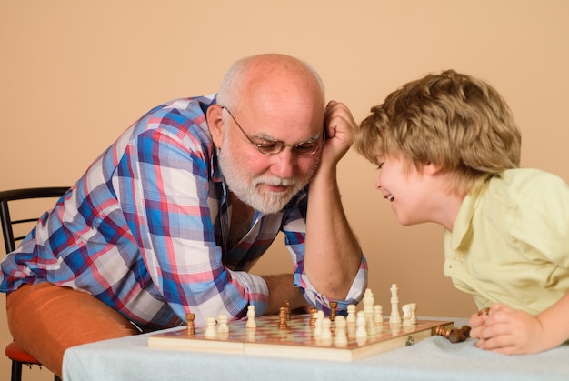 おじいちゃんとチェスをしているチェスの子供おじいさんが孫にチェスの家族関係を教えている