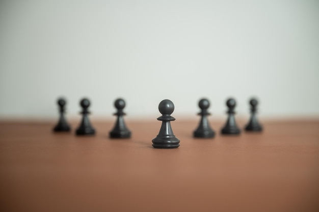 Figure di pedine degli scacchi disposte in una linea a forma di piramide su superficie marrone