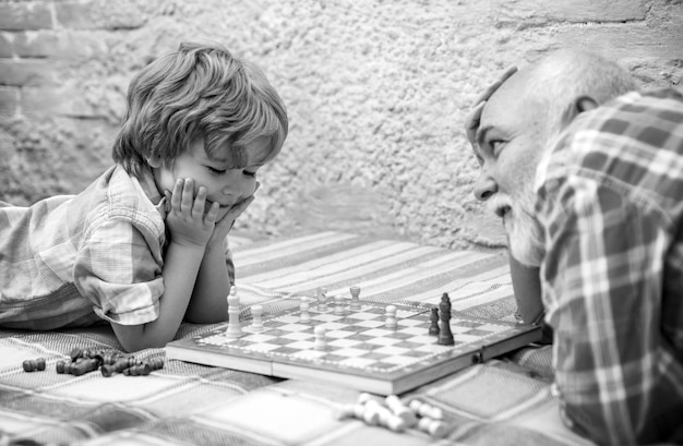 Photo chess piece grandfather and grandson concept handsome grandpa and grandson are playing chess while