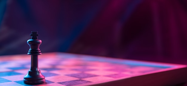 Chess pieces on a chessboard on a dark background shot in neon pink-blue colors