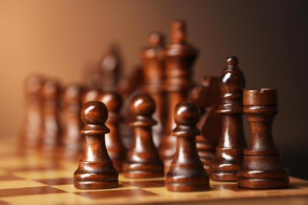 Chess pieces and game board on brown background