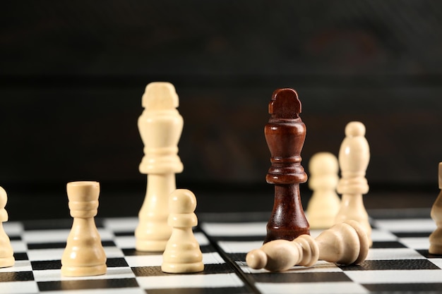 Chess pieces and game board on wooden background