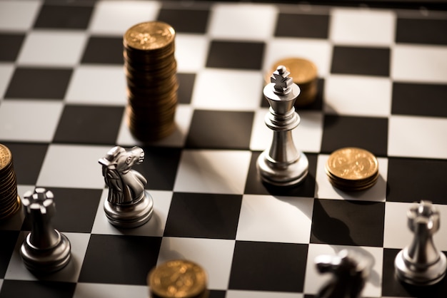 chess pieces and stack of coins on a chessboard