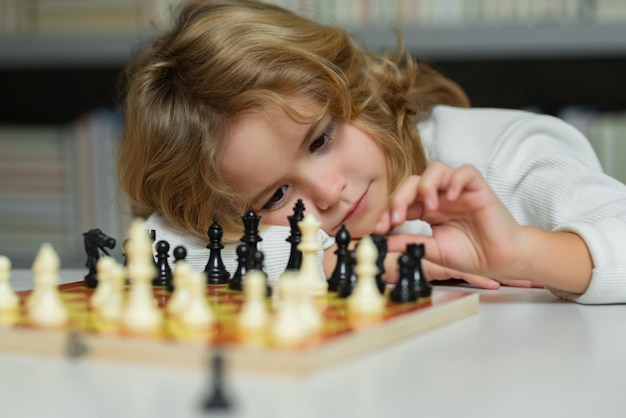 Chess school child think or plan about chess game kids\
education concept intelligent smart and clever school kids kids\
early development boy kid playing chess at home portrait close\
up