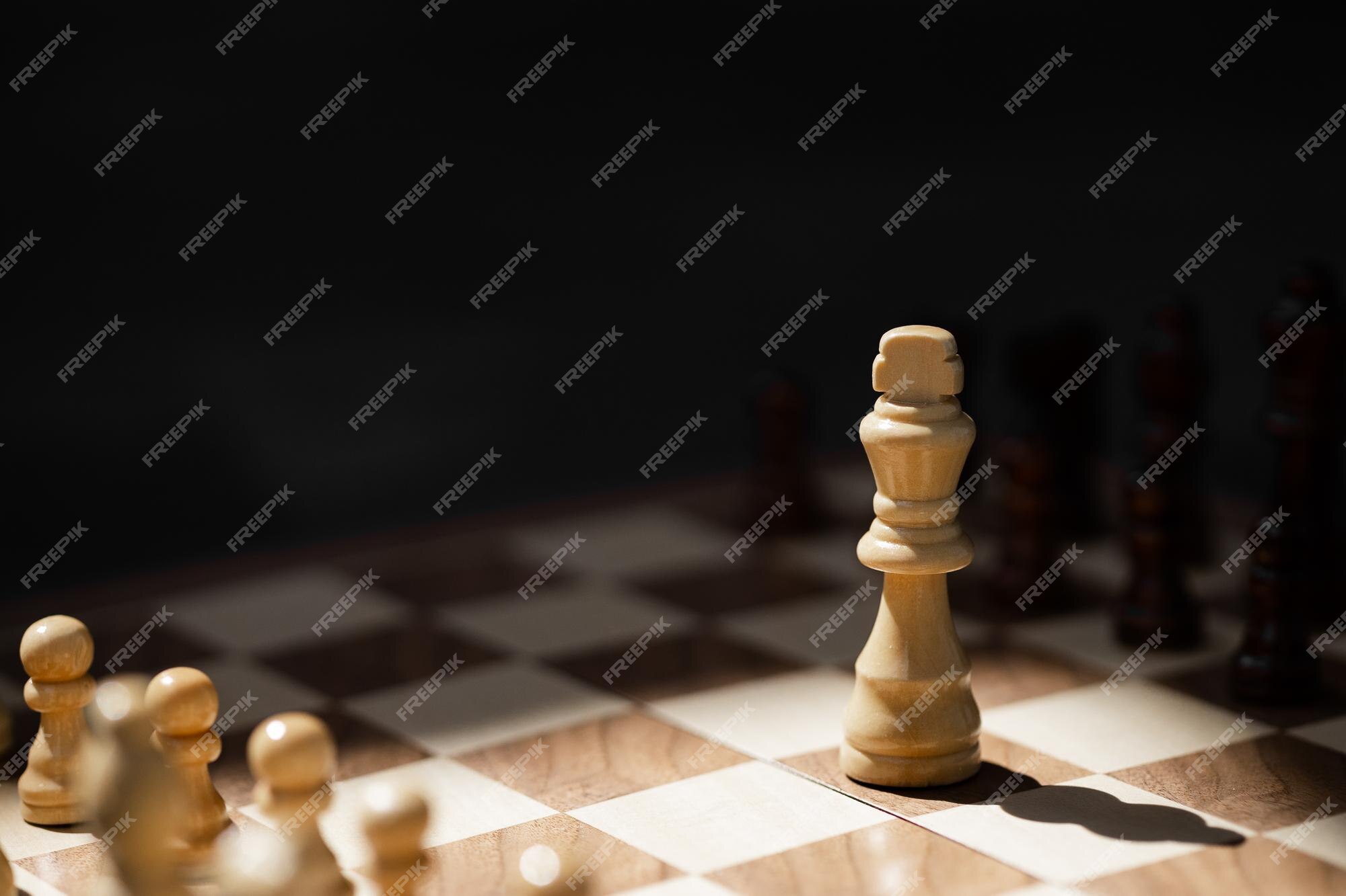 Premium Photo  Closeup of chess pieces on the chessboard under the lights  with a blurry background