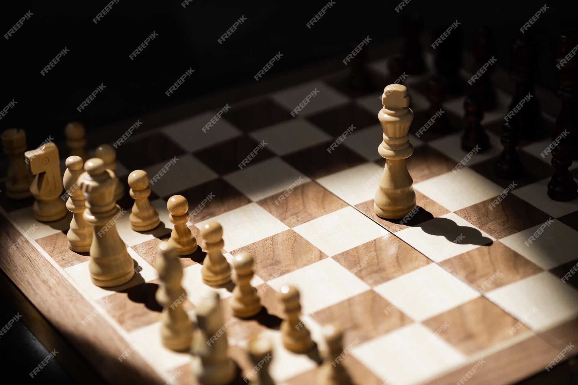 Premium Photo  Closeup of chess pieces on the chessboard under the lights  with a blurry background