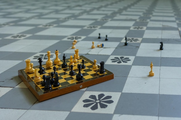 Chessboard with scattered figures stands on checkered floor